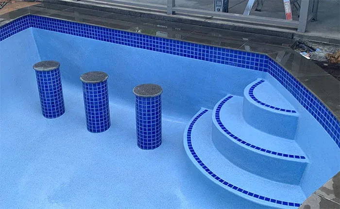 Custom tiled pool with built-in bar stools and entertainment seating area
